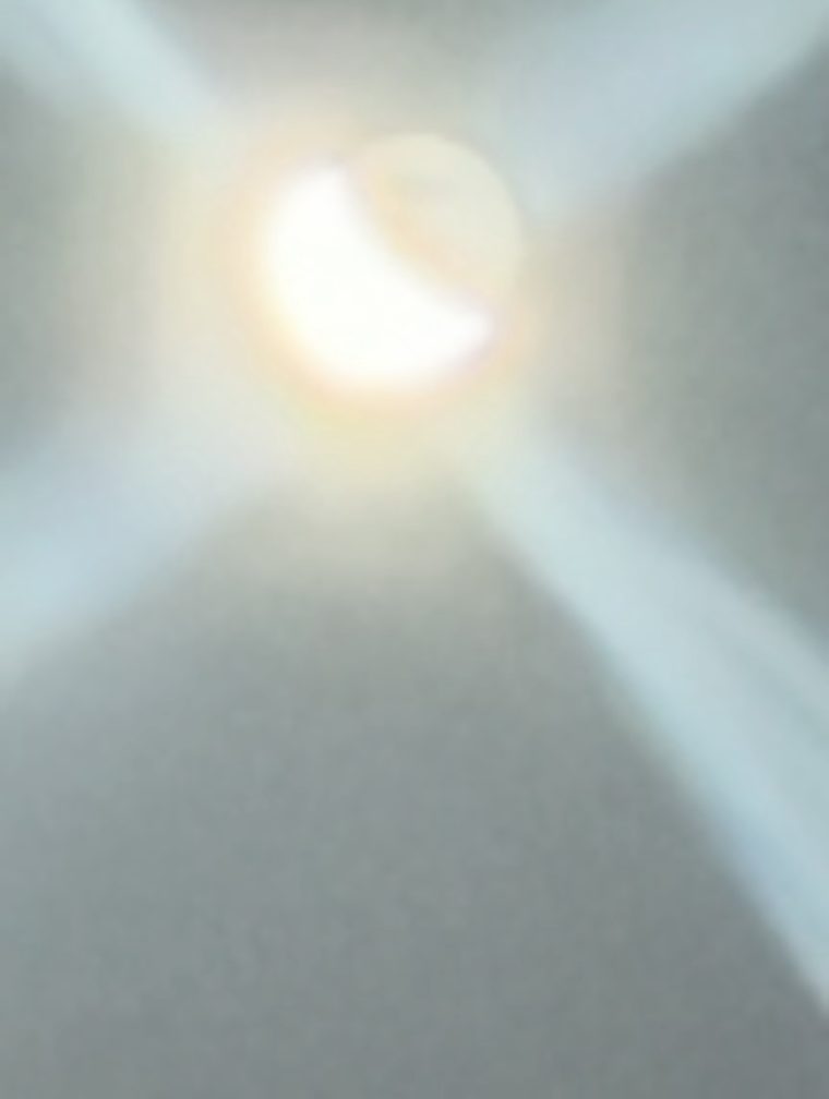 A zoomed photo of the crescent moon with four arms of light forming a cross centered on the disc